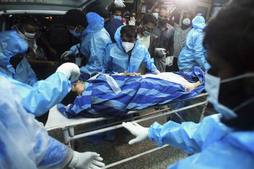 Health workers transfer an inured passenger on a stretcher to take her inside a hospital in Kozhikode.